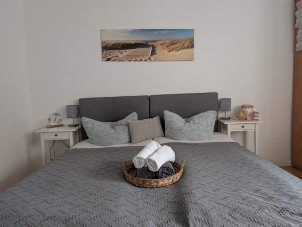 Gemütliches Schlafzimmer mit Doppelbett, dekorativen Kissen und Handtüchern in einem Korb.